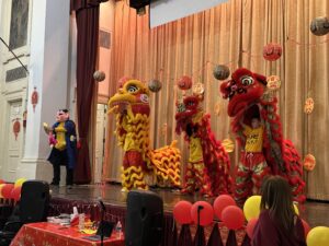 3 lion dancers with heads held up high on stage.