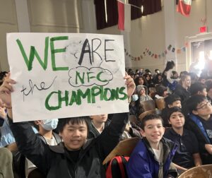 Students in the assembly holding a sign that says "We Are the NFC CHampions"